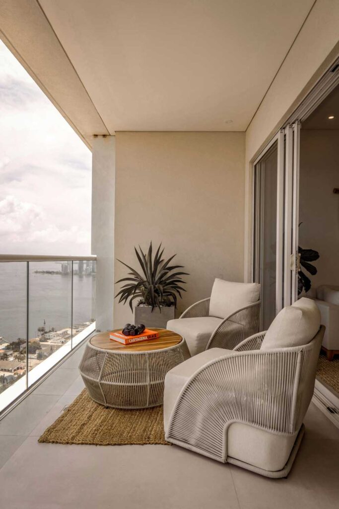 Balcone moderno con arredi minimal, colori neutri e materiali sostenibili come legno e metallo.