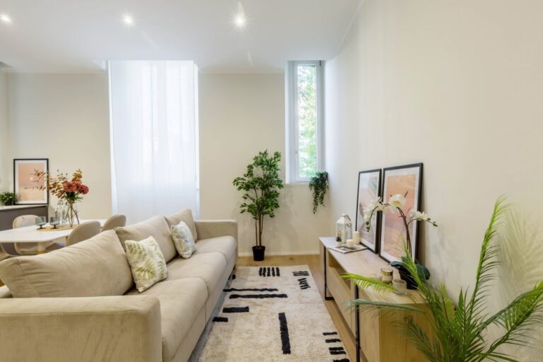 Zona living moderna con divano beige, arredi su misura e luce naturale, interior design AD2 LAB Milano