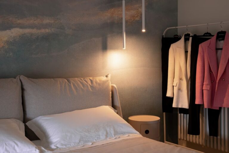 Dettaglio della testiera letto con luce calda e abiti esposti, interior design su misura a Monza