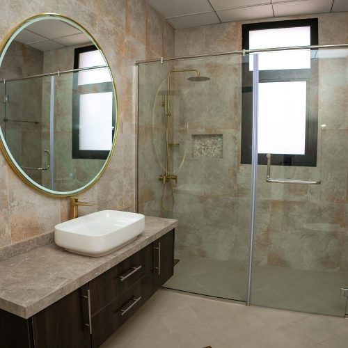 Bagno elegante con vasca freestanding, doccia vetrata, doppio lavabo tondo e rubinetteria nera