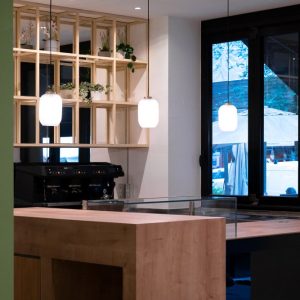 vista sul retrobancone con lampade a sospensione, scaffalature in legno e macchina del caffè nera