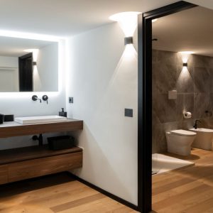 Bagno moderno con doppio lavabo in legno e specchio retroilluminato