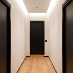 Corridoio moderno con porte nere e illuminazione a LED sul soffitto