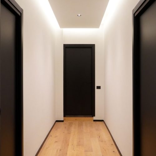 Corridoio moderno con porte nere e illuminazione a LED sul soffitto