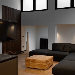 Zona TV con boiserie in legno, luci LED e divano scuro
