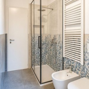 bagno con doccia walk-in, piastrelle decorative blu e sanitari sospesi