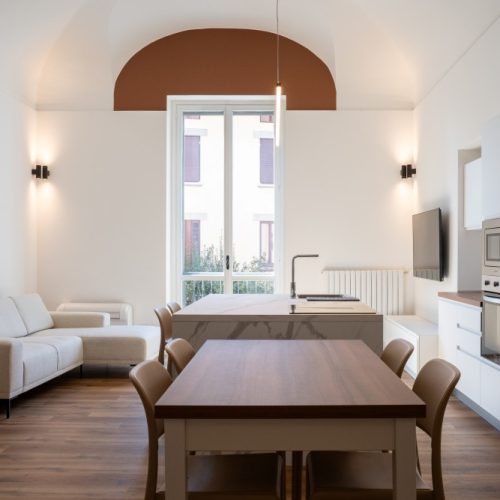 Zona giorno con cucina bianca, isola centrale e soffitto voltato, ristrutturazione a Varese
